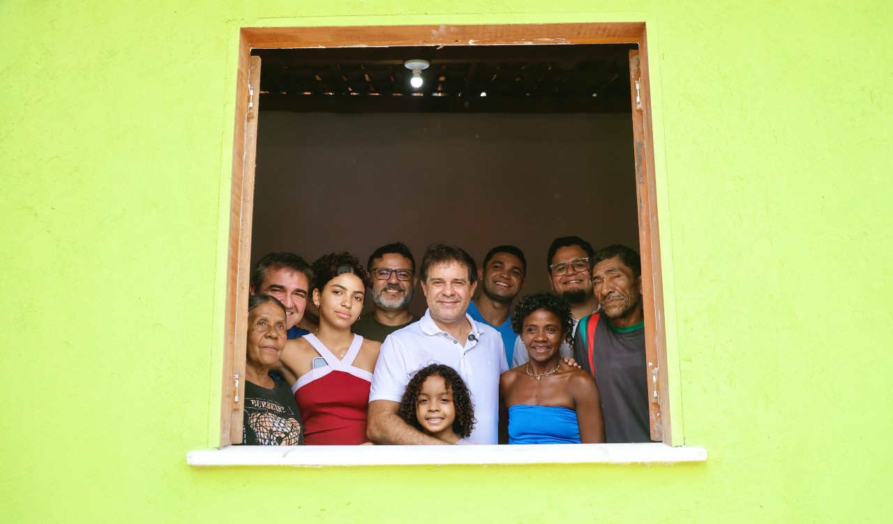 grupo de pessoas posa para a foto na janela da casa que foi reformada